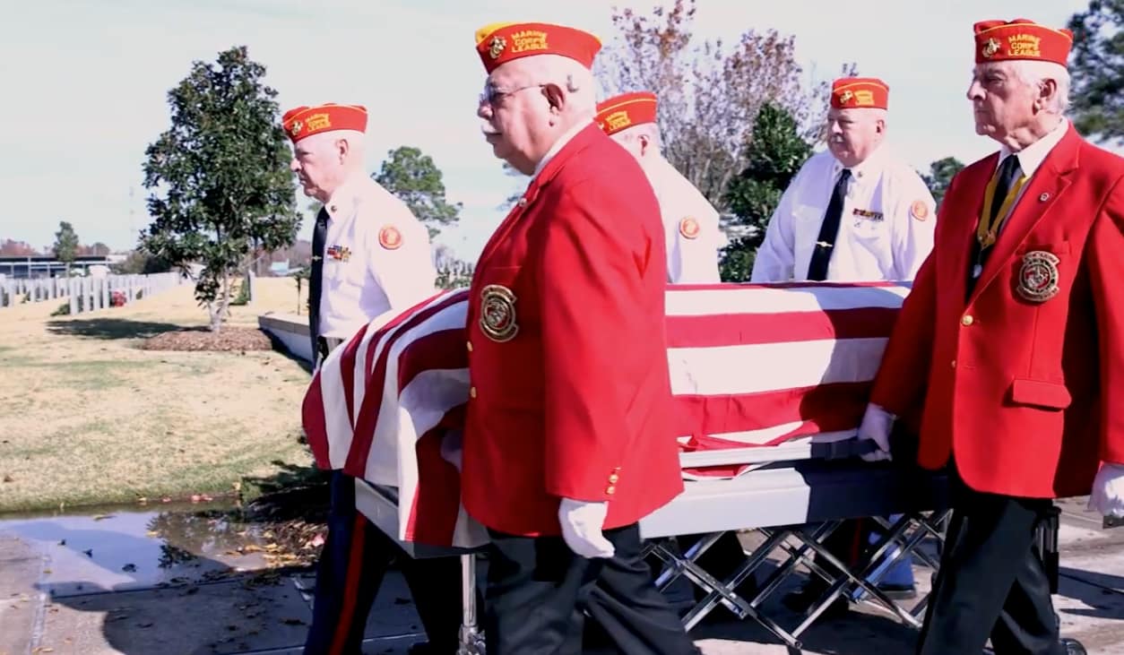 Marine Corps League Detachment 1490 honor guard carrying a flag-draped casket during a military funeral ceremony